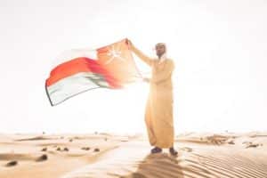 Mann mit Oman Flagge ind er Wüste